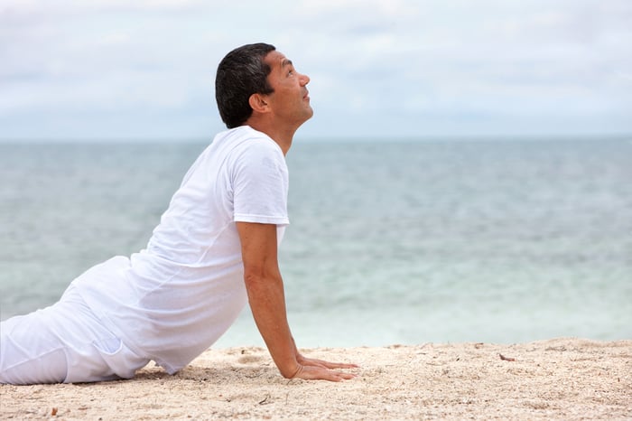 Fit man doing yoga exercises at the beach