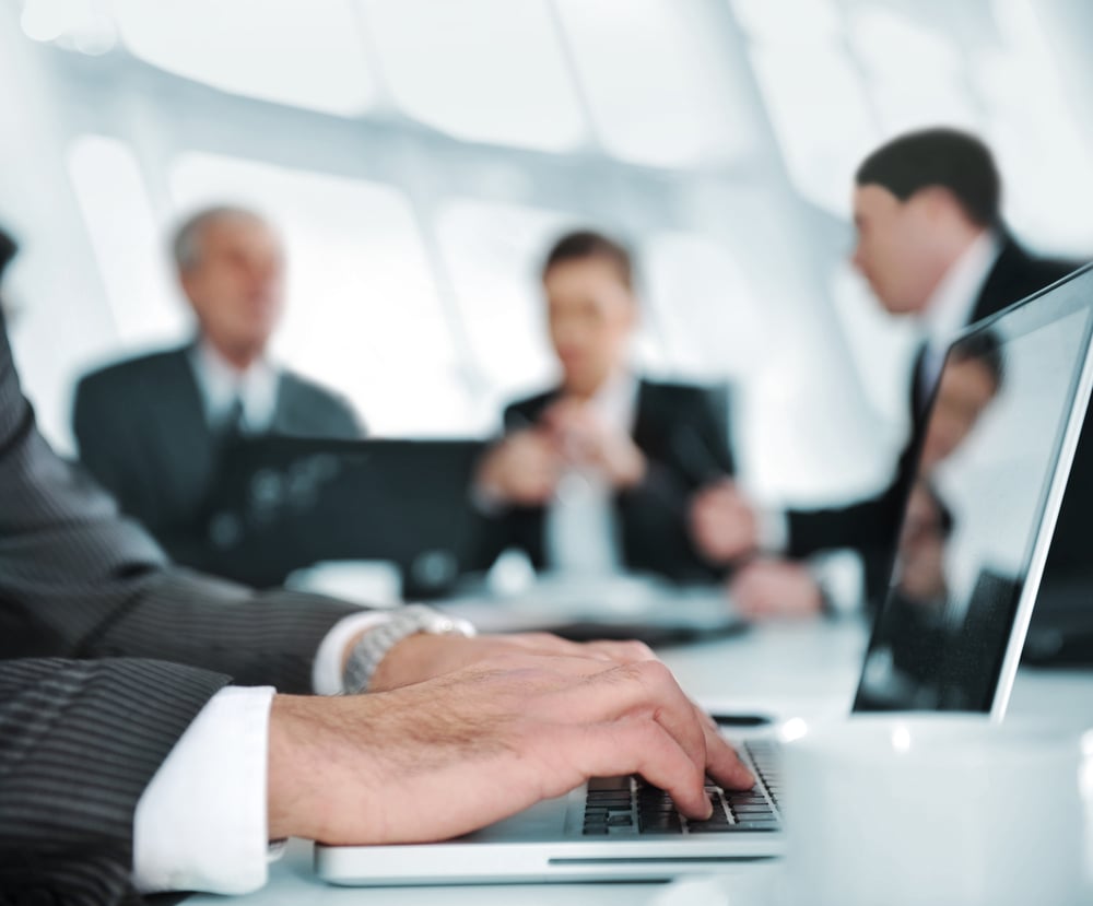 Typing on laptop while the business group having meeting-1